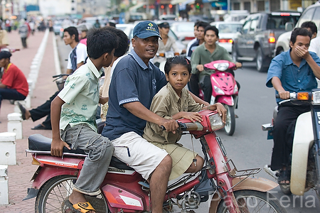 Asia;Camboya;Sudeste_Asiatico;tropico;zonas_tropicales;gente;personas;sociedad;razas_y_etnias;oriental_asiatico;camboyanos;entorno_urbano;calles_y_avenidas;trafico;vehiculos;vehiculos_circulando;motos_circulando;trafico_denso;caravanas;gente_en_moto;motociclista;motorista;motoristas;moto_con_tres_pasajeros;motorista_sin_casco